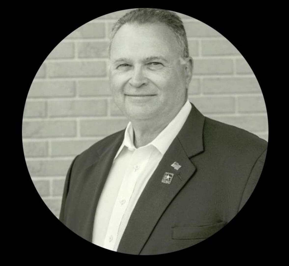 A man in suit and tie standing next to brick wall.